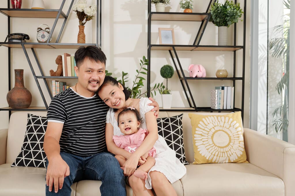 happy vietnamese-man sitting sofa home design hugging his pretty young wife